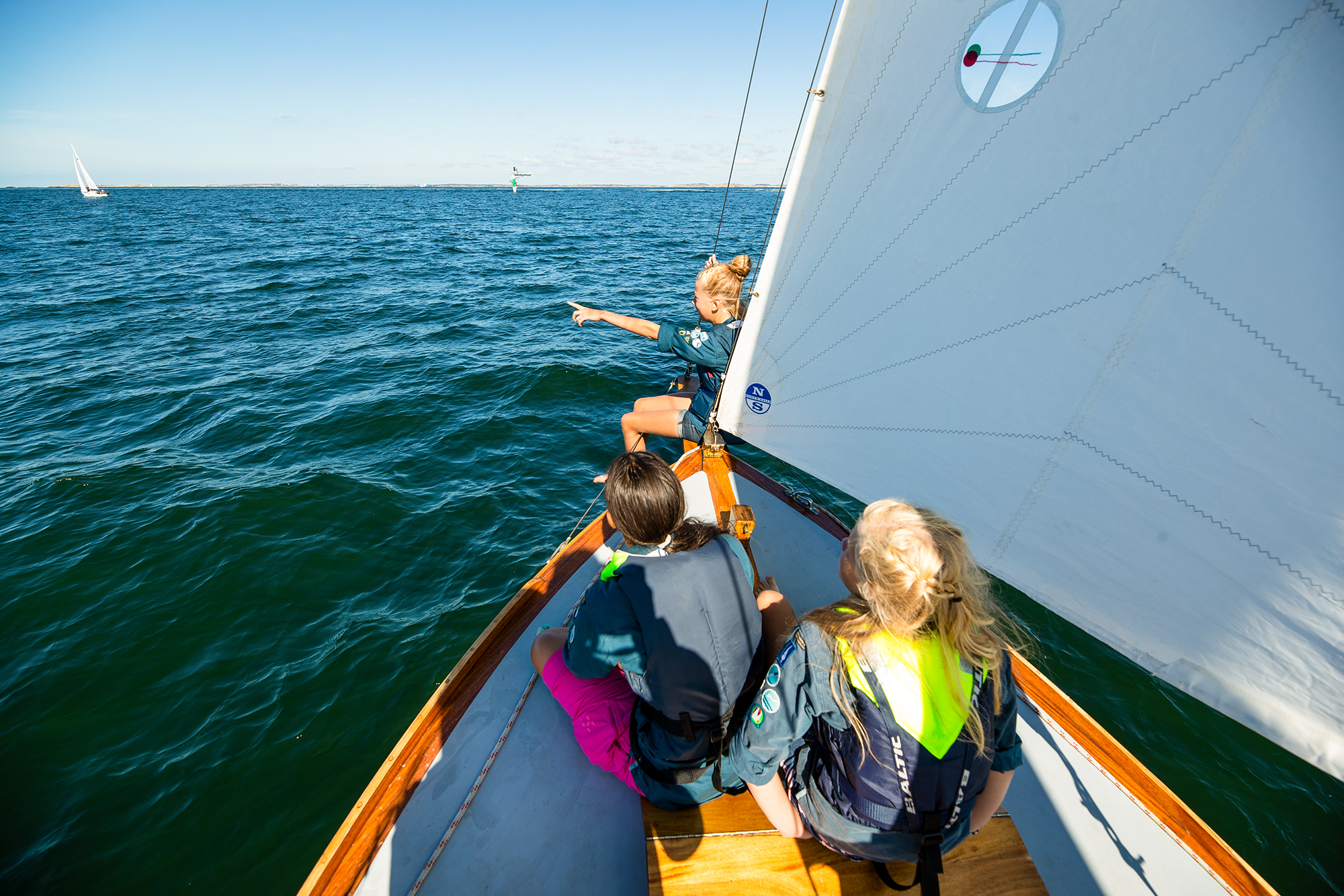 Ett par scouter sitter i fören på en segelbåt