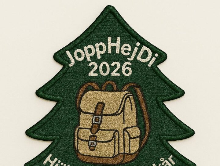 Brodyrmärke i form av en grön gran med texten "JoppHejDi 2026" högst upp, en beige ryggsäck i mitten och texten "Hjälteby Sjöscoutkår" längst ner.