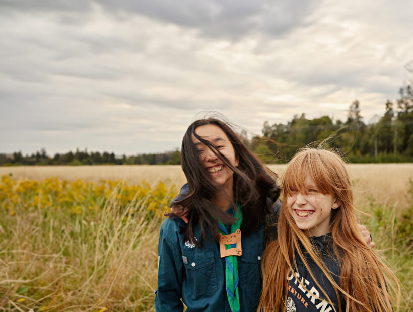 Två glada scouter står på ett fält