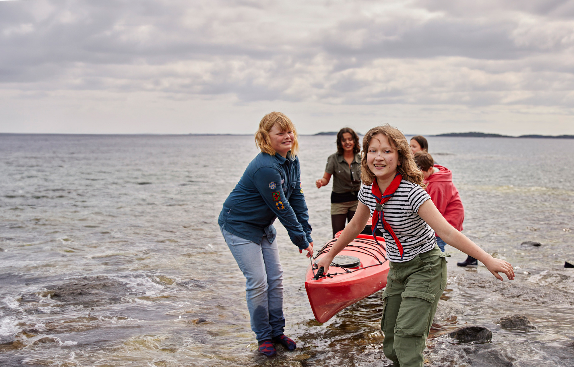 En scoutpatrull drar upp en kanot ur vattnet.